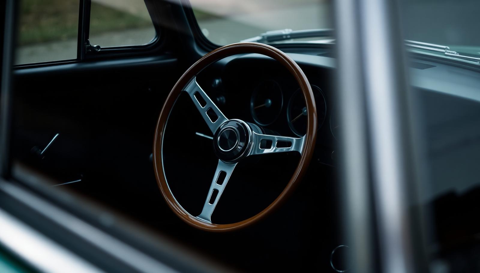 Large thin-rimmed wood-rimmed steering wheel and chrome column inside a classic British sports saloon